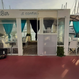 Struttura in legno per ristorante sul porto di Ostia (Roma), con chiusure laterali in Cristal avvolgibili. Teli trasparenti fino a terra, apribili completamente nella stagione estiva.